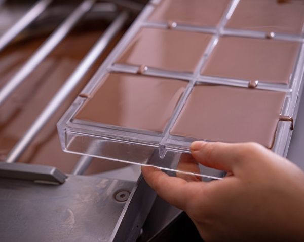 Choc Affair team member pouring chocolate into a chocolate mould