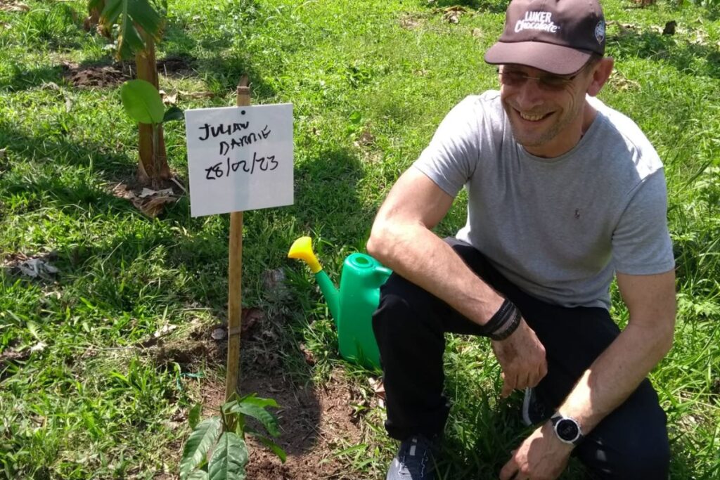 A man crouched down next to a newly planted tree