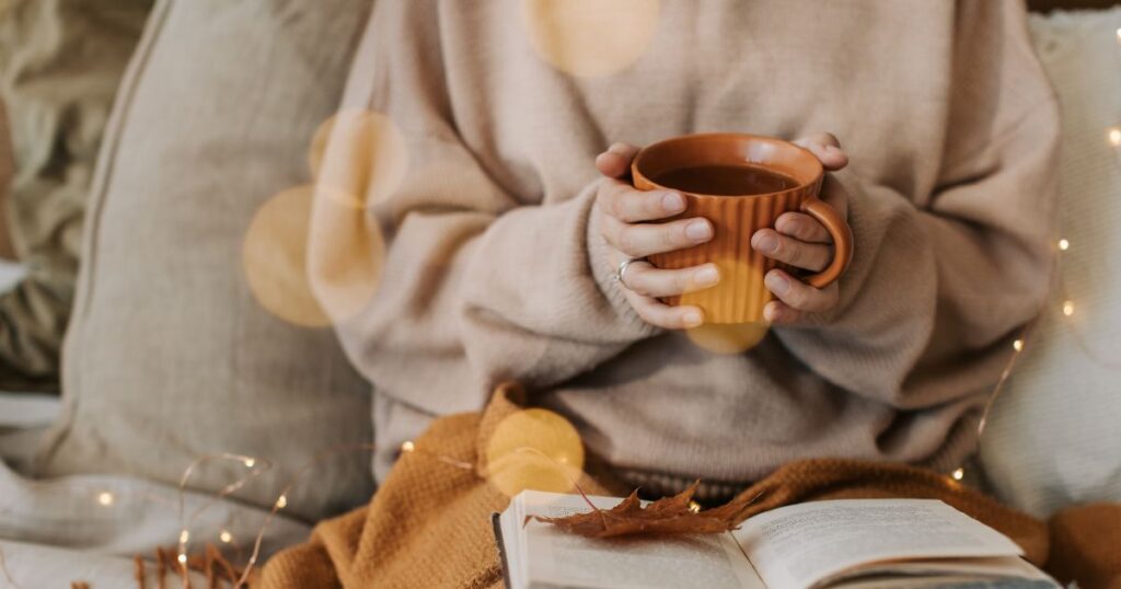 a woman holding a mug of coffee whilst reading a book
