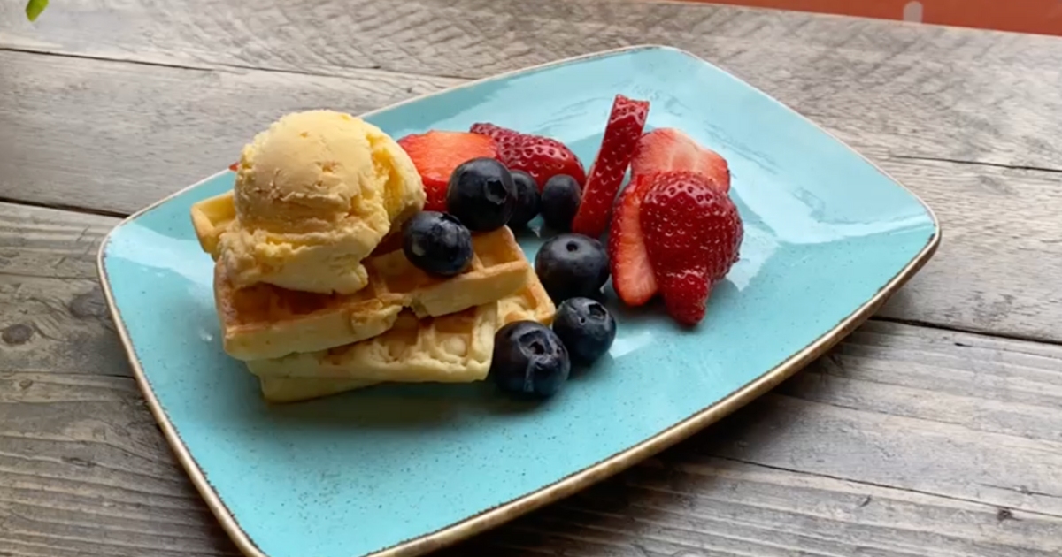 A plate of waffles with ice cream and fruit
