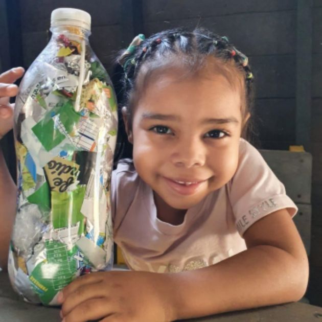 Young girl holding a plastic bottle full of recycled waste